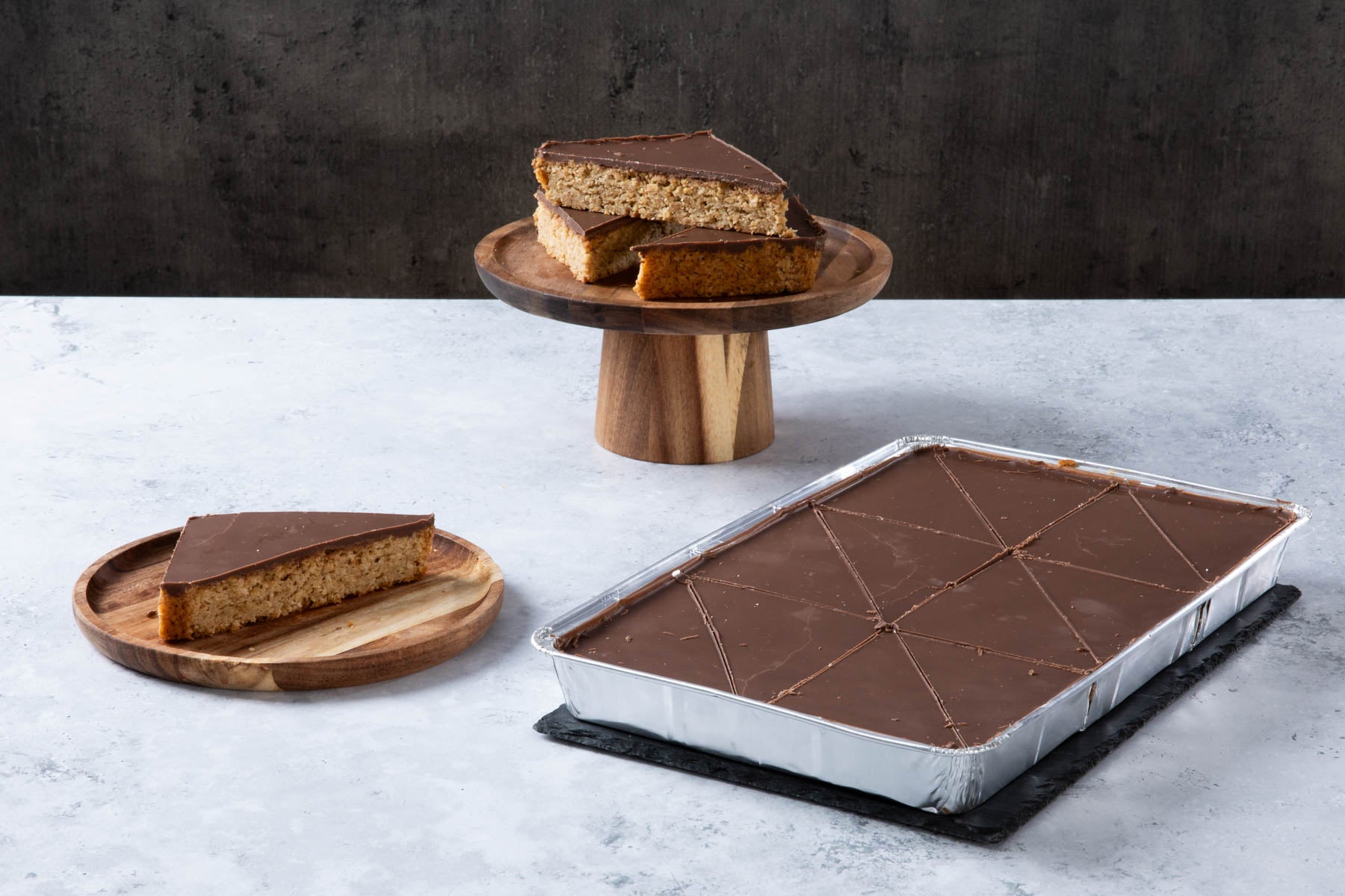 LHMC004-174.jpg Chocolate-topped oat traybake slices on wooden plates.