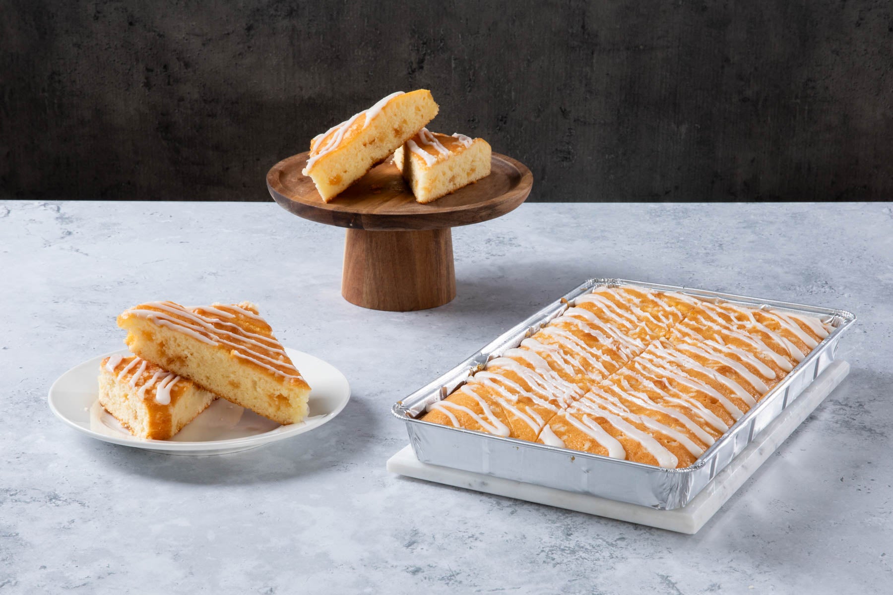 LHMC004-188.jpg Lemon drizzle cake slices with white icing in a baking tray.