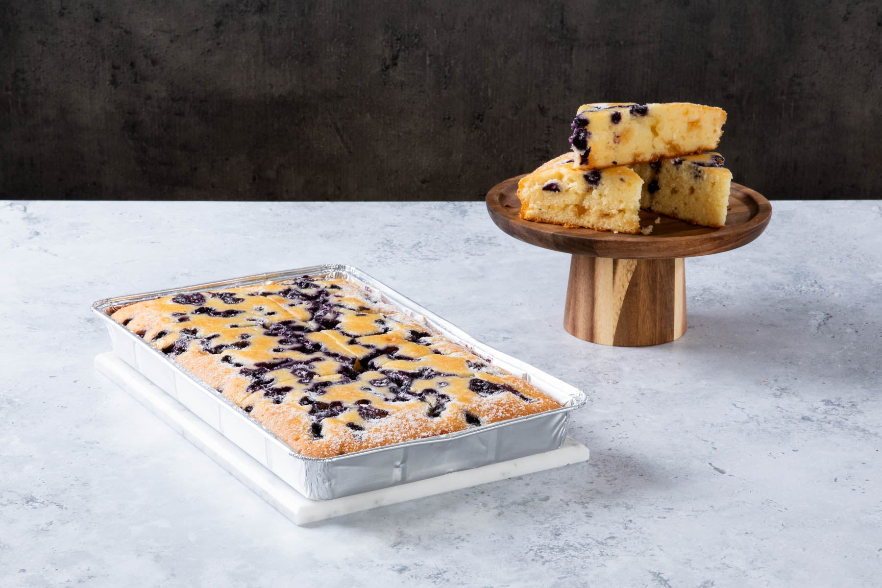 LHMC004-239.jpg Blueberry crumble cake slices on a wooden cake stand and tray.