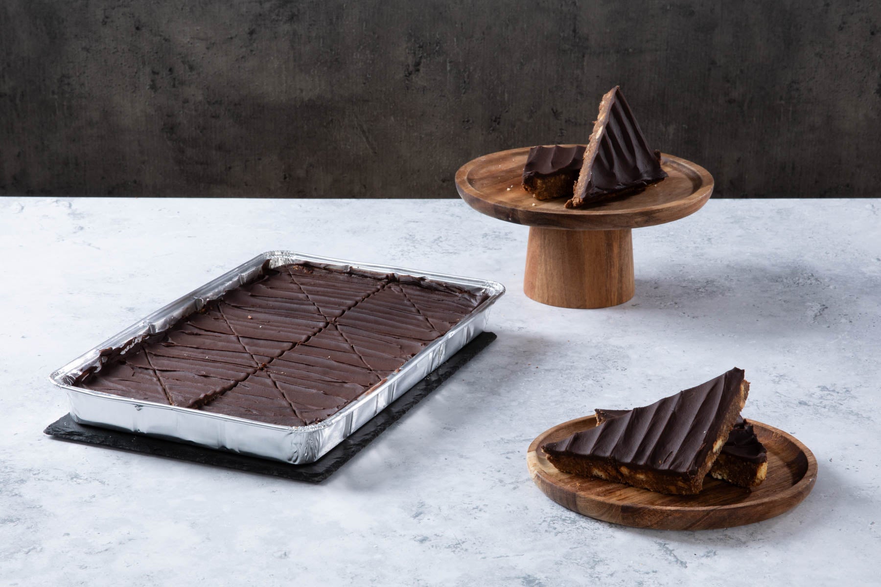 LHMC004-312-1.jpg Chocolate cake with creamy frosting and chocolate topping on a wooden board.