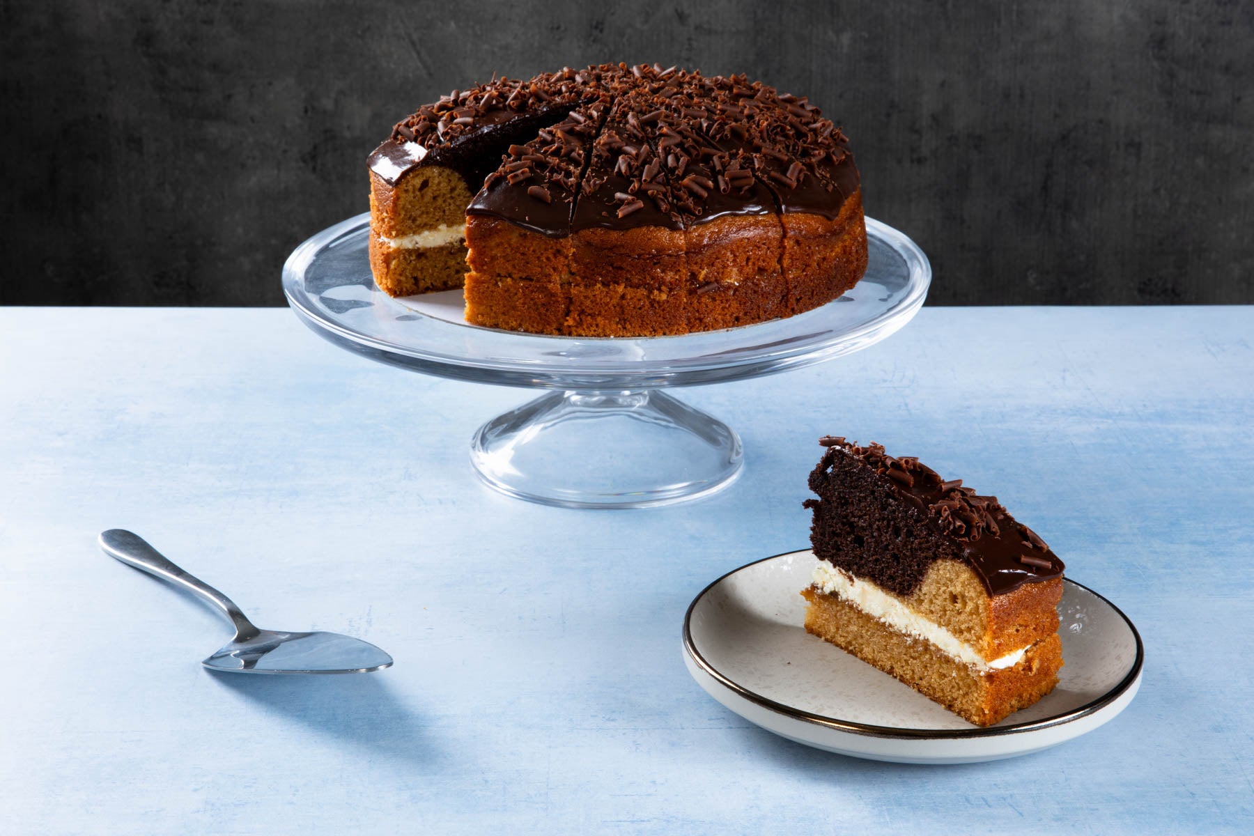 LHMC007-220.jpg Lemon drizzle cake with lemon icing on a wooden board.
